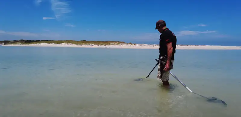 Man Metal Detecting On The Beach